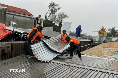 Bộ đội Biên phòng tỉnh Thừa Thiên-Huế phối hợp với chính quyền địa phương hỗ trợ các gia đình bị thiệt hại lợp lại, gia cố mái nhà. (Ảnh: TTXVN phát)