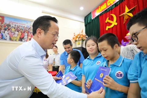 Giám đốc Sở Giáo dục và Đào tạo Hà Nội Trần Thế Cương trao tặng các món quà tới học sinh của 3 ngôi trường chuyên biệt. (Ảnh: Thanh Tùng/TTXVN)