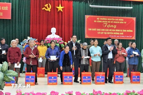 Bộ trưởng Bộ Kế hoạch và Đầu tư Nguyễn Chí Dũng và lãnh đạo UBND tỉnh tặng quà cho các hộ dân bị ảnh hưởng lũ lụt tại huyện Hương Khê. (Ảnh: Hữu Quyết/TTXVN)