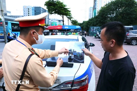 Lực lượng CSGT cho tài xế xe khách xem lại hình ảnh vi phạm để làm căn cứ xử phạt theo quy định pháp luật. (Ảnh: Phạm Kiên/TTXVN)