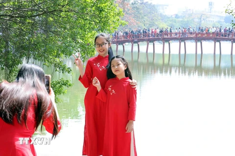 Người dân ghi lại hình ảnh đẹp bên cầu Thê Húc, quận Hoàn Kiếm, trong mùng 2 Tết. (Ảnh: Phạm Kiên/TTXVN)
