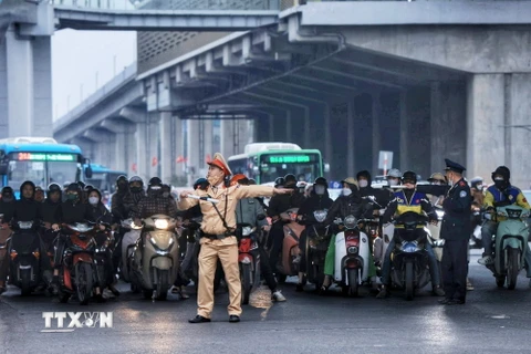 Lực lượng Cảnh sát Giao thông phân luồng các phương tiện để tránh ùn tắc tại ngã tư Nguyễn Xiển-Khuất Duy Tiến-Nguyễn Trãi. (Ảnh: Tuấn Anh/TTXVN)