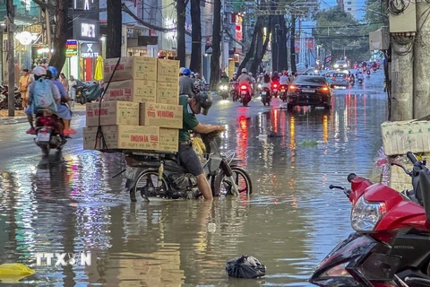 Người dân gặp khó khăn khi di chuyển do nước ngập trên đường Nguyễn Trãi, quận Ninh Kiều, thành phố Cần Thơ. (Ảnh: Thanh Liêm/TTXVN)