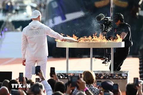 Ca sỹ Pháp JuL thắp sáng vạc lửa bằng ngọn đuốc Olympic Paris 2024, tại buổi lễ ở cảng Marseille (Pháp) ngày 8/5. (Ảnh: THX/TTXVN)