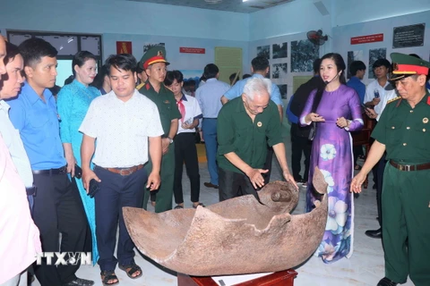 Các cựu chiến binh xem một miếng bom được trưng bày tại “Huyền thoại Trường Sơn.” (Ảnh: Đoàn Hữu Trung/TTXVN)