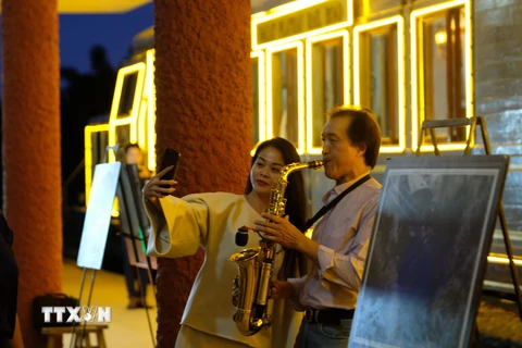 Du khách thích thú với màn trình diễn saxophone tại sân ga Đà Lạt trước giờ tàu hỏa khởi hành. (Ảnh: Nguyễn Dũng/TTXVN)