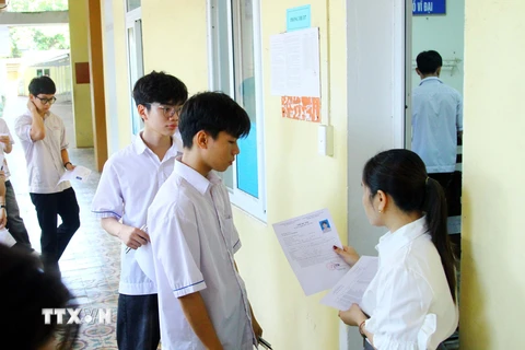 Giám thị kiểm tra thẻ dự thi của các thí sinh trước khi vào phòng thi tại điểm thi Trường THPT Đào Duy Từ, thành phố Đồng Hới, tỉnh Quảng Bình. (Ảnh: Tá Chuyên/TTXVN)