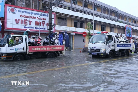 Lực lượng Cảnh sát Giao thông thành phố Nam Định dùng xe chuyên dụng đưa người dân và phương tiện qua điểm ngập lụt tại khu vực chân cầu Đò Quan. (Ảnh: Công Luật/TTXVN)