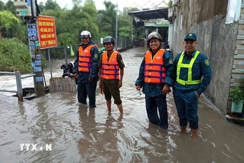 Lực lượng chức năng phường Tân Phước Khánh, thành phố Tân Uyên, tỉnh Bình Dương, có mặt để hỗ trợ người dân, phân luồng giao thông và cảnh báo những đoạn đường ngập sâu, nước chảy siết do mưa lớn. (Ảnh: TTXVN)