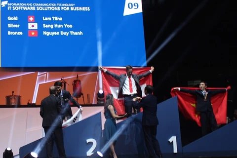 Thí sinh Nguyễn Duy Thanh giương cao lá cờ Tổ quốc trên bục trao giải. (Ảnh: Tổng cục Dạy nghề)