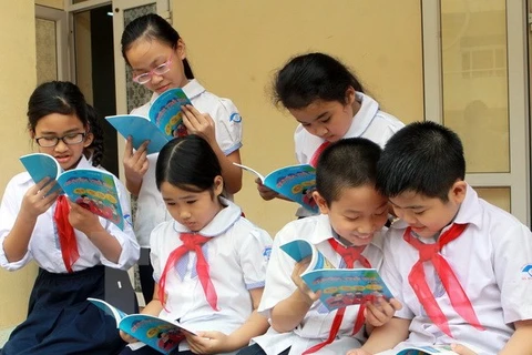 Các em học sinh đang đọc sách "Quyền trẻ em". (Ảnh minh hoạ: Nguyễn Thủy/TTXVN)