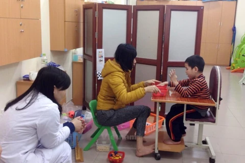 Người mẹ hướng dẫn trẻ tự kỷ học tại Bệnh viện Nhi Trung ương. (Ảnh: PV/Vietnam+)