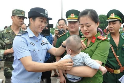 Lực lượng chức năng Việt Nam tiếp nhận em bé bị bán sang Trung Quốc. (Ảnh:Nguyễn Hoàng/TTXVN)