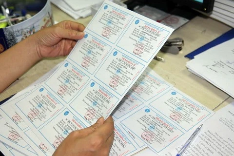 Kiểm tra thẻ bảo hiểm y tế trước khi phát cho người dân. (Ảnh: PV/Vietnam+)