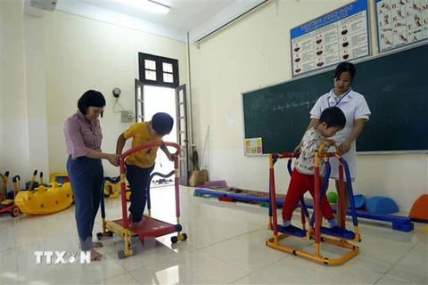 Nhân viên công tác xã hội tập phục hồi chức năng cho các học sinh khuyết tật. (Ảnh: Phạm Kiên/TTXVN)