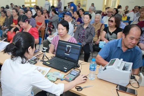 Cơ quan bưu điện tổ chức chi trả lương hưu cho người lao động. (Ảnh: PV/Vietnam+)