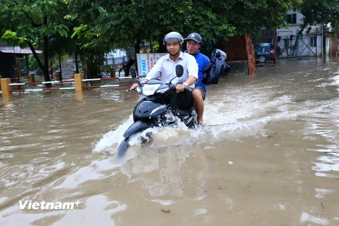 Tại khu vực phường Thịnh Liệt, quận Hoàng Mai, người dân di chuyển rất khó khăn trong điều kiện nước ngập. Trong thời điểm sáng sớm, có vị trí nước ngập quá đầu gối. (Ảnh: Minh Sơn/Vietnam+)