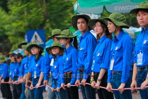 Hình ảnh những sinh viên tình nguyện lập ‘hàng rào sống’ giúp thí sinh sang đường. (Ảnh: Minh Sơn/Vietnam+)