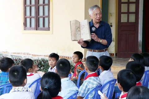 Giáo sư Nguyễn Huy Mỹ - người con của dòng họ Nguyễn Huy trò chuyện với học sinh trường Tiểu học Trường Lộc (Hà Tĩnh) về cuốn sách “Hoàng hoa sứ trình đồ.” (Ảnh: TTXVN)