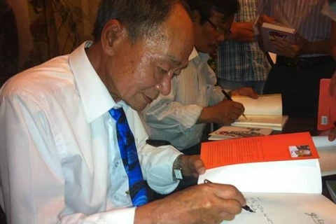 Nhà thơ Du Tử Lê ký tặng độc giả trong buổi ra mắt "Giỏ hoa thời mới lớn" tại Hà Nội năm 2014. (Ảnh: PV/Vietnam+)