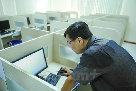 Cán bộ kỹ thuật kiểm tra máy tính trước giờ thi. (Ảnh: Lê Minh Sơn/Vietnam+) 
