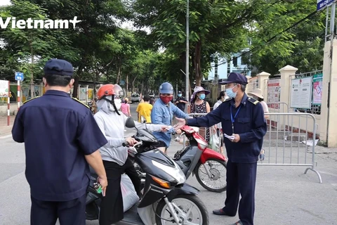 Lực lượng chức năng kiểm tra phiếu tại cổng chợ (Ảnh: Hoàng Đạt/Vietnam+)