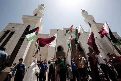 Người dân Palestine phất cờ ủng hộ Qatar sau khi nước này bị nhiều quốc gia cắt quan hệ ngoại giao. (Nguồn: AFP)