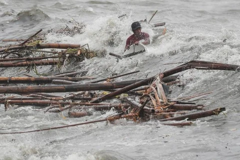 Một người Philippines cố bơi giữa dòng nước lũ để cứu tài sản. (Nguồn: CNN)