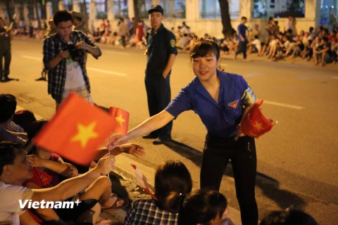 Sinh viên tình nguyện phát cờ Tổ quốc cho nhân dân. (Ảnh: Minh Sơn/Vietnam+)