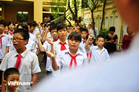 Các em học sinh xếp hàng ngay ngắn, cùng thầy giáo hướng dẫn hát Quốc ca bằng ngôn ngữ cử chỉ (thủ ngữ). (Ảnh: Võ Phương/Vietnam+)