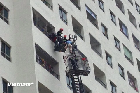 Cảnh sát chữa cháy phải dùng búa, rìu để phá cửa giải cứu những người bị mắc kẹt trong tòa nhà. (Ảnh: PV/Vietnam+)