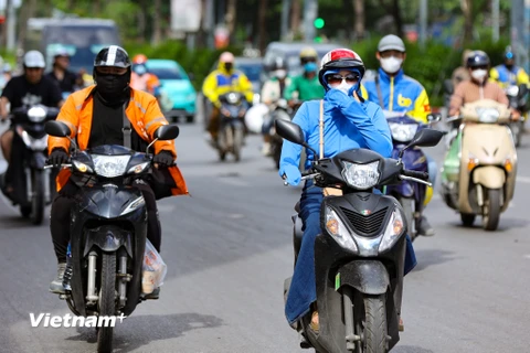 Người dân mặc kín để chống chọi với nắng nóng. (Ảnh: Hoài Nam/Vietnam+)