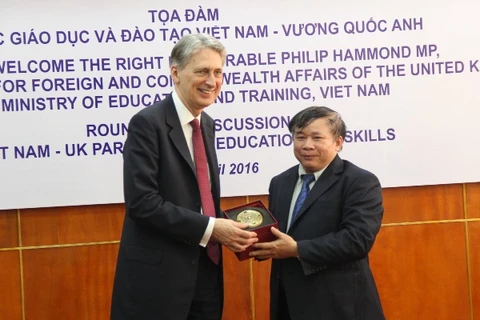 Thứ trưởng Bùi Văn Ga tặng quà lưu niệm cho Ngoại trưởng Anh Philip Hammond. (Ảnh: CTV/Vietnam+)