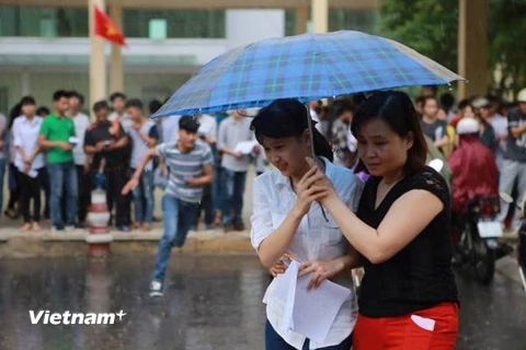 Thí sinh rời trường thi môn Vật lý ở Hà Nội dưới trời mưa. (Ảnh: Lê Minh Sơn/Vietnam+)