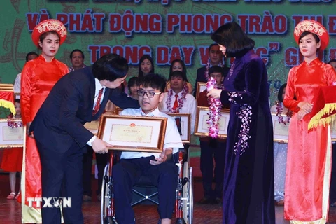 Bộ trưởng Phùng Xuân Nhạ và Phó Chủ tịch nước Đặng Thị Ngọc Thịnh trao hoa và bằng khen cho em Nguyễn Thiên Phú. (Ảnh: Quý Trung/TTXVN)
