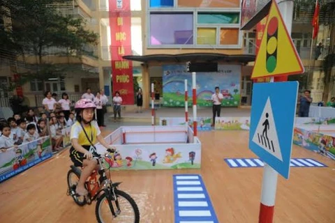 Các em học sinh hào hứng khi được học an toàn giao thông trên mô hình. (Ảnh: CTV/Vietnam+)