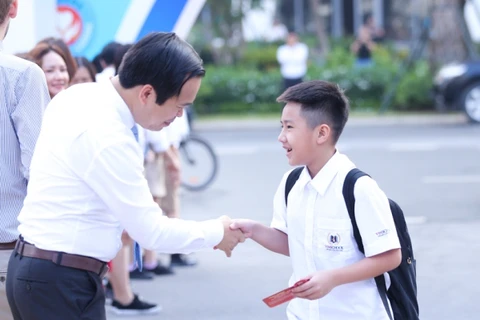 Học sinh được trao những cái bắt tay đầy yêu thương cho một năm học mới. (Ảnh: CTV/Vietnam+)