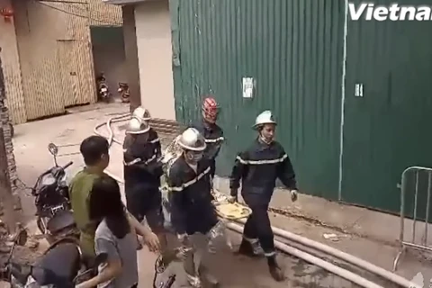 Lực lượng phòng cháy chữa cháy đưa thi thể các nạn nhân ra ngoài. (Ảnh: PV/Vietnam+)