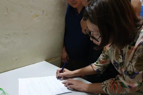 Bà Trần Thị Hồng Hạnh ký vào bản tường trình. (Ảnh: Thùy Giang/Vietnam+)