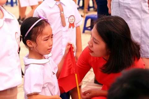 Cô giáo ân cần động viên em học sinh lớp 1 trong ngày đầu tiên đến trường tại trường Tiểu học Gia Quất, quận Long Biên (Hà Nội). (Ảnh: Danh Lam/TTXVN)