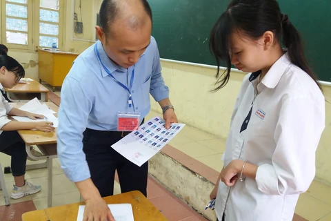 Giám thị kiểm tra thông tin của thí sinh trước khi vào phòng thi Trung học phổ thông quốc gia. (Ảnh: Phạm Mai/Vietnam+)
