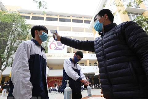 Học sinh Hà Nội được đo thân nhiệt, sát khuẩn trước khi vào trường. (Ảnh: Thành Đạt/TTXVN)