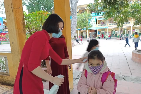 Học sinh Hà Nội được đo thân nhiệt trước khi vào lớp. (Ảnh: Phạm Mai/Vietnam+)
