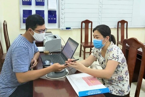 Cán bộ tuyển sinh Trường Tiểu học Nghĩa Dũng (quận Đống Đa, Hà Nội) hỗ trợ phụ huynh làm hồ sơ. (Ảnh: PV/Vietnam+)