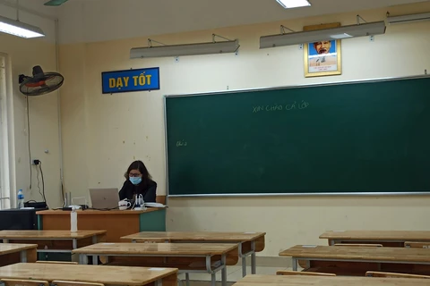 Tấm bảng đen với dòng chữ "Xin chào cả lớp" nhưng chỉ có giáo viên, không có một học sinh nào tại Trường Trung học phổ thông Trần Nhân Tông. (Ảnh: Phạm Mai/Vietnam+)