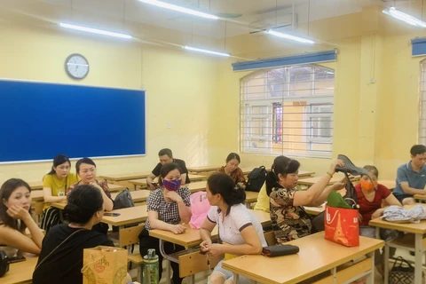 Các phụ huynh của điểm thi Trường Trung học cơ sở Nguyễn Công Trứ ngồi chờ con trong phòng học tại điểm chờ Trường Tiểu học Nguyễn Trung Trực. (Ảnh: CTV)