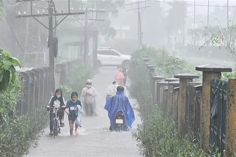 Ngập lụt ở Thừa Thiên-Huế khiến người dân gặp khó khăn khi tham gia giao thông. (Ảnh: Mai Trang/TTXVN)