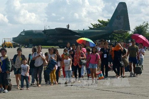 Những người sống sót sau bão Haiyan lên máy bay vận tải quân sự rời khỏi thành phố Tacloban để đến Manila ngày 14/11. AFP/TTXVN