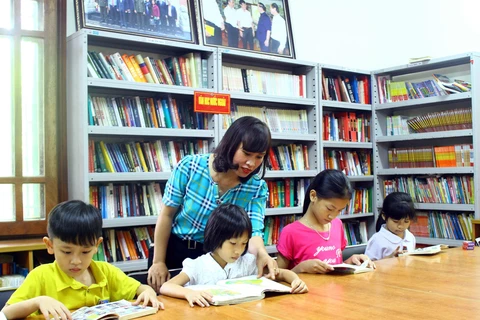 Các em học sinh chăm chú đọc sách tại thư viện Làng Sen. (Ảnh: Tá Chuyên/TTXVN)