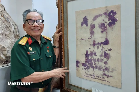Họa sỹ Lê Duy Ứng và phiên bản của bức chân dung Bác Hồ vẽ bằng máu. (Ảnh: Minh Thu/Vietnam+)